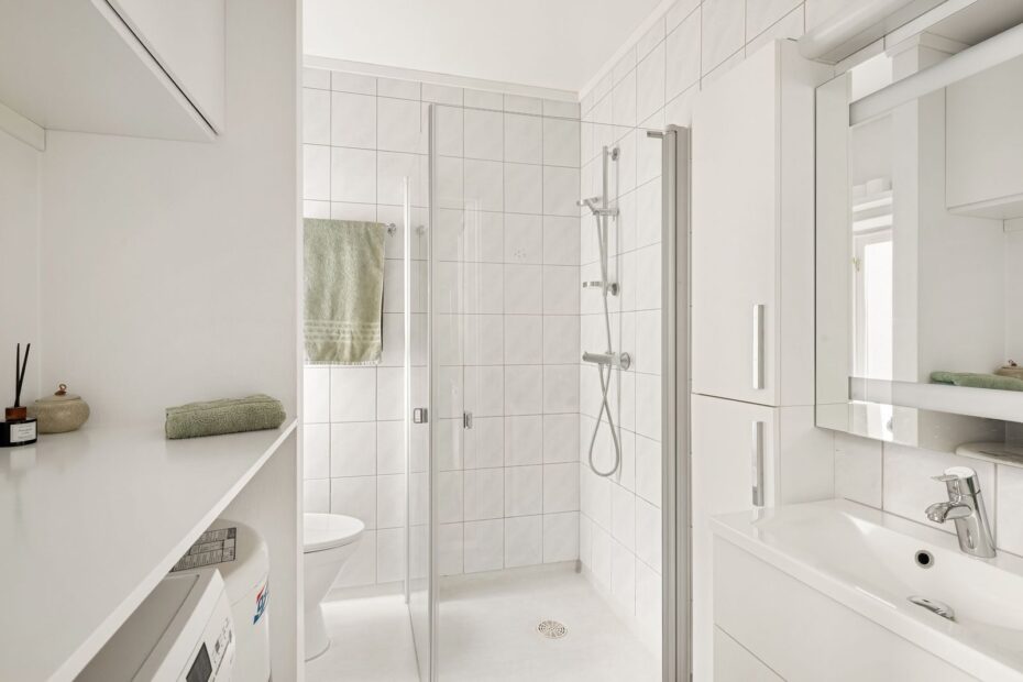 Bright, minimalist white bathroom featuring a sleek design with glass shower and modern fixtures.