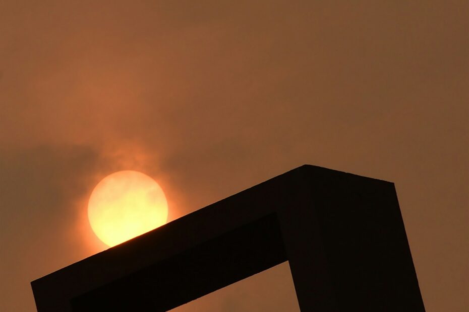 the sun is setting in the sky behind a building